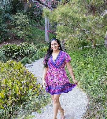 a reviewer in a v-neck purple and blue floral dress