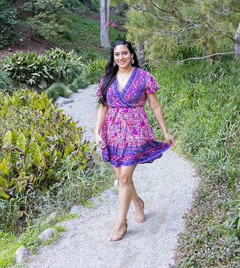 a reviewer in a v-neck purple and blue floral dress