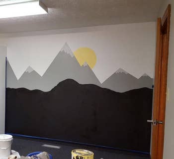 a reviewer photo of a wall mural with a portion of the painting done with chalkboard paint 