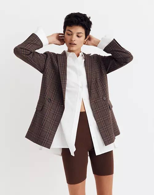 a model posing in a brown plaid blazer over a white button down and brown bike shorts