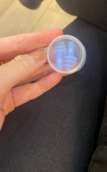 another reviewer holding the blue ear plugs in their clear case