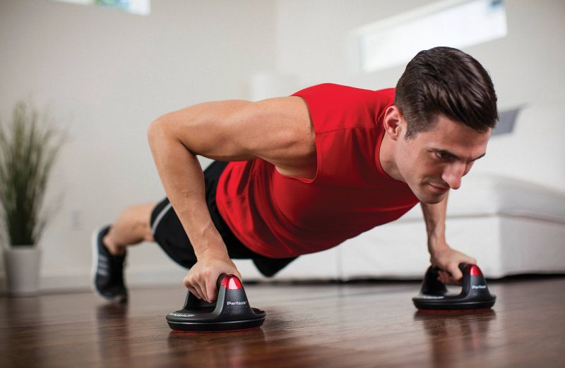 model in plank position while holding push-up bars in both hands