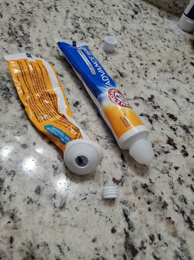 an empty tube of toothpaste and a full tube with the reusable silicone cap