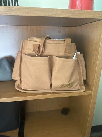 Utility tote bag with pockets on a wooden shelf; a pen is visible in one pocket