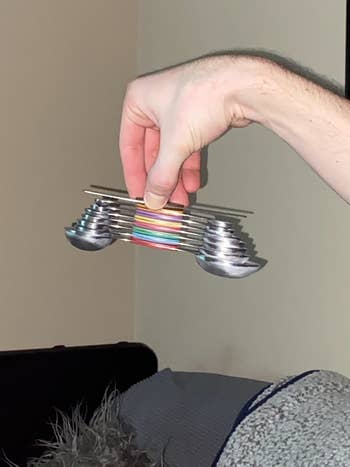 reviewer holding the stack of spoons suspended to show the strength of the magnet