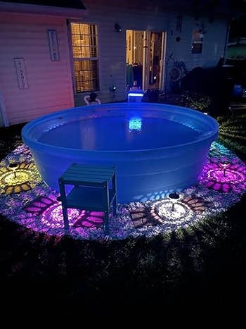 A circular outdoor excavation with LED lights and decorative stones, creating a stylish nighttime plot ambiance