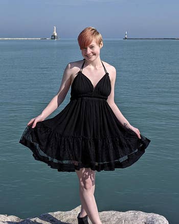 reviewer in a breezy black halter sundress by the sea