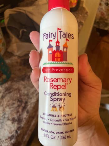 Hand holding a bottle of Fairy Tales Rosemary Repel Conditioning Spray, lice prevention hair product