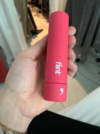 Reviewer holding their pink portable lint roller, closed in its compact case