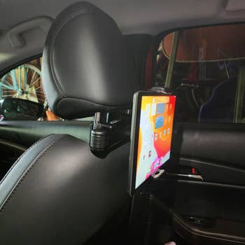 A tablet mounted on the back of a car seat's headrest