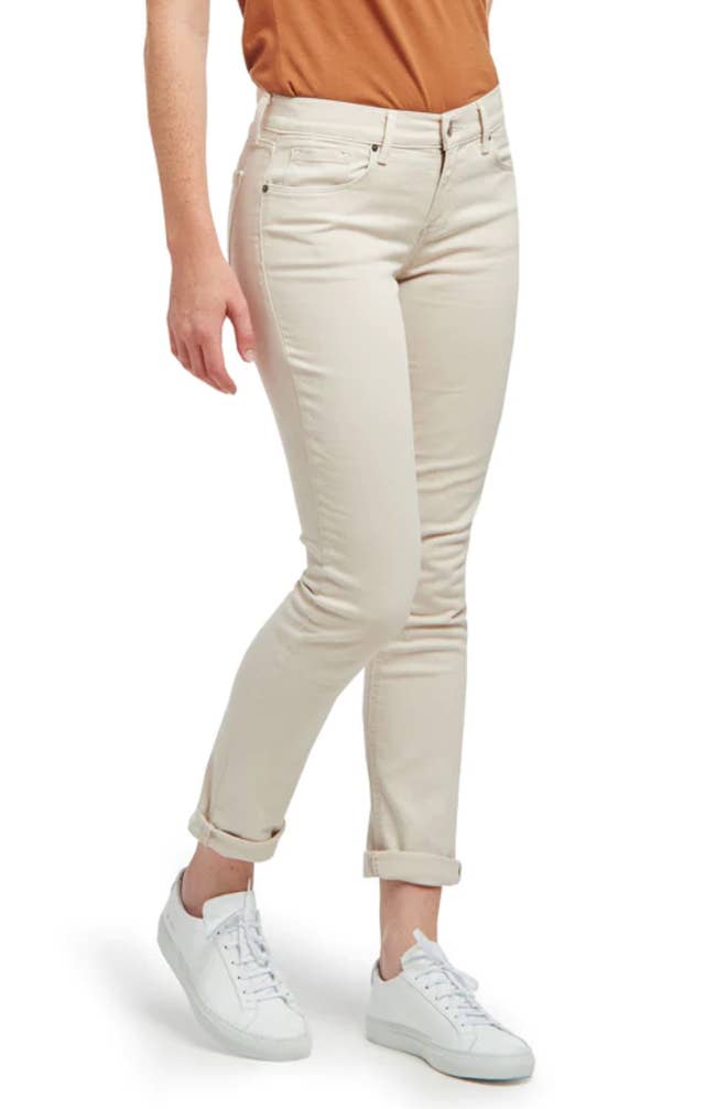 A model wearing light beige jeans folded by the ankles