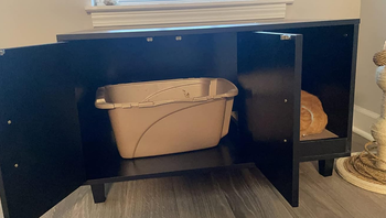 a reviewer photo of the cabinet doors on the enclosure open to show the litter box inside 