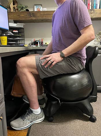 reviewer's tall husband sitting on the exercise ball chair, showing it's large enough even for him