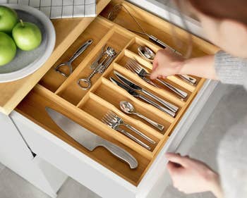 Person organizing kitchen utensils in a drawer organizer