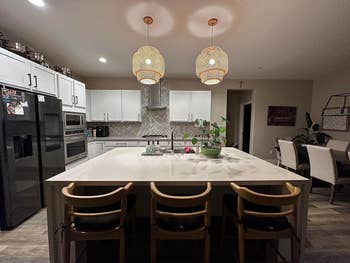 Modern kitchen with two rattan pendant lights over an island with bar stools