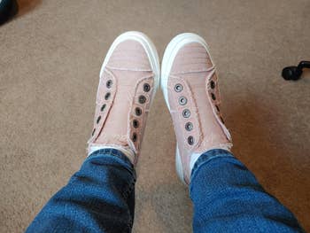 Casual sneakers with frayed edges and metallic eyelets, worn with bluish jeans, shown from a top-down view