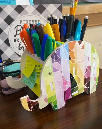 Reviewer's colorful elephant holder holding a bunch of pencils and sharpies, with sticky notes on the side