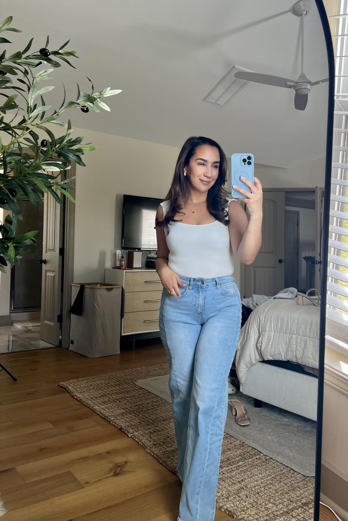 Person takes a reflector  selfie successful  a modern   bedroom, wearing a achromatic  vessel  apical  and bluish  jeans