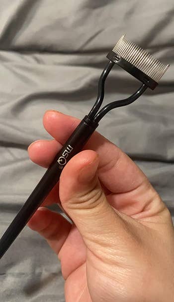 reviewer hand holding the black eyelash separator comb