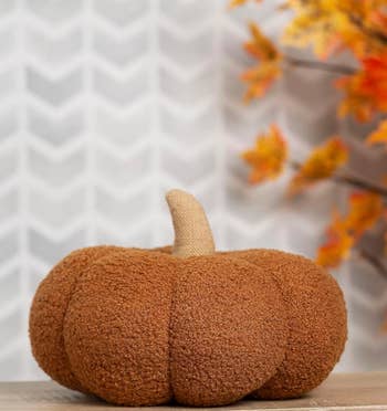 Decorative cloth pumpkin connected a array with autumn leaves successful the background. Perfect for seasonal location decoration