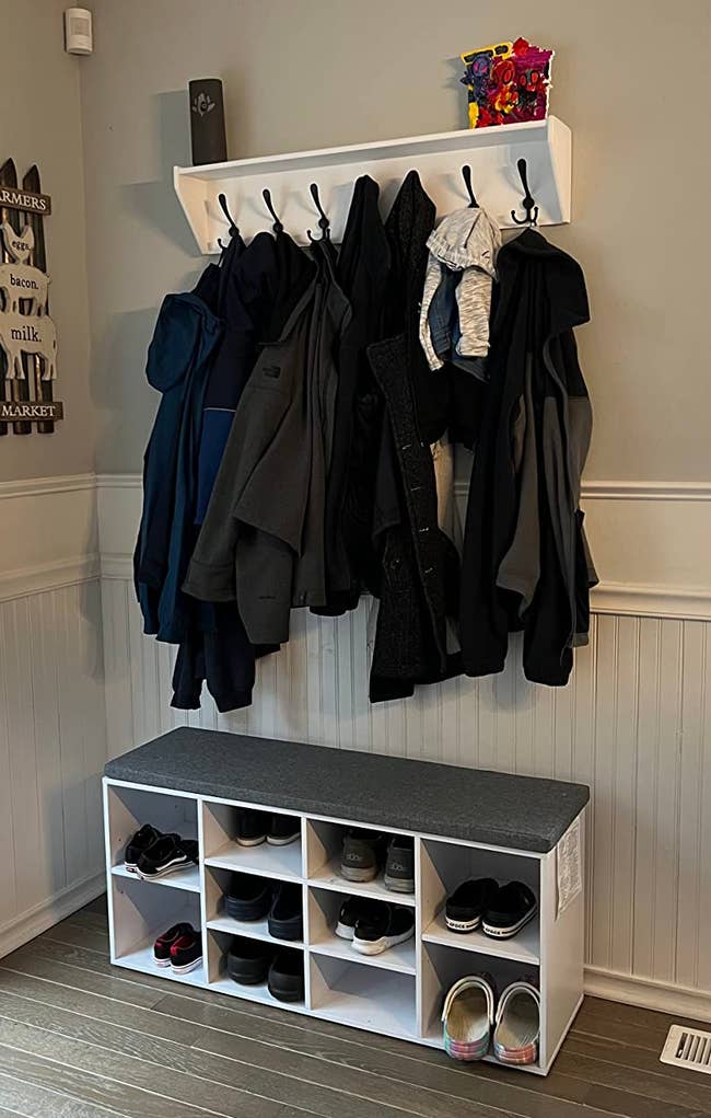 Entryway with coats hanging and a shoe rack filled with various shoes