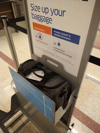 Sign showing baggage size checker for United Airlines with a carry-on bag for airline travel