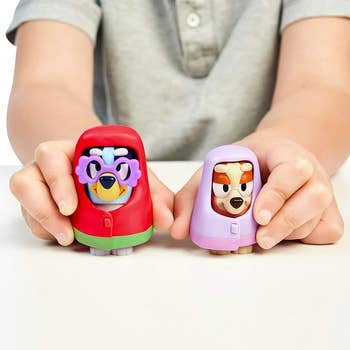 child holding two dog toys dressed up as grandmas