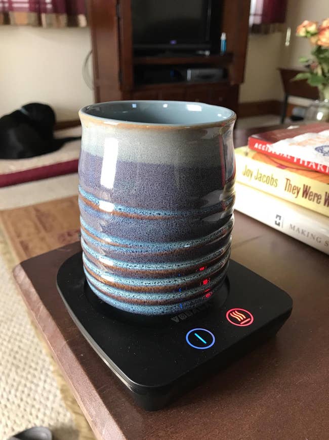 reviewer's ceramic coffee cup on the black warmer with light indicators on