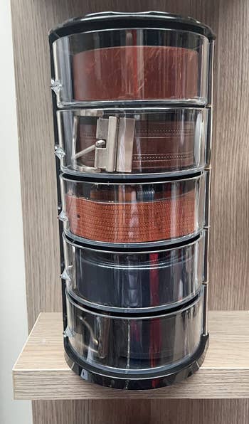 reviewer's acrylic belt organizer with five belts in it