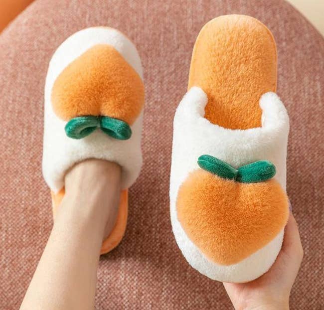 Model is wearing the white and orange slippers with a big fluffy peach on the top