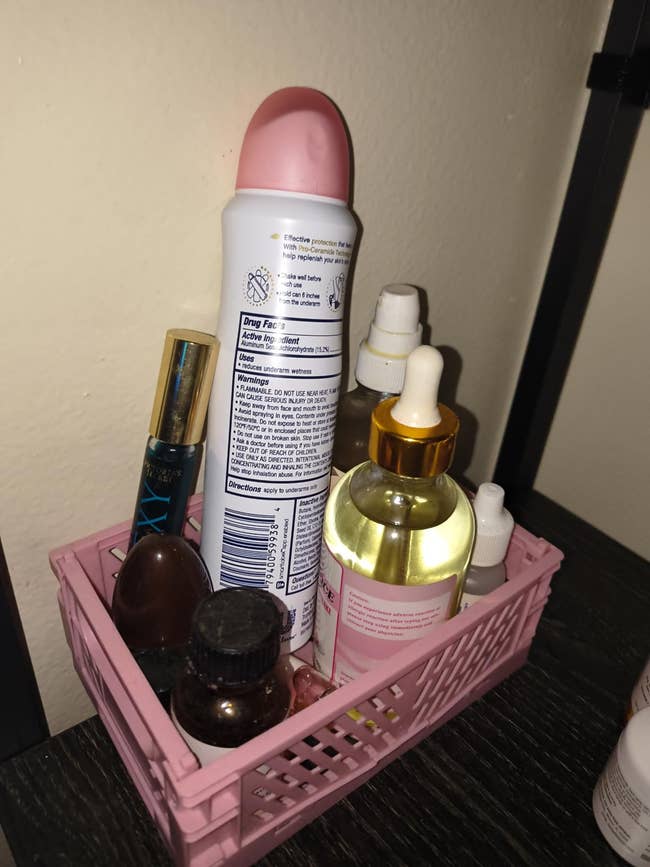 Beauty products organized successful  a pinkish  handbasket  connected  a shelf, including deodorant, dropper bottles, and spray