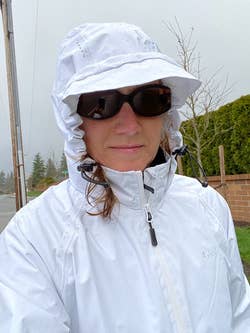 A reviewer wearing the jacket in white with the hood on their head