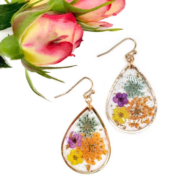 gold teardrop shaped earrings with clear centers with colorful dried flowers