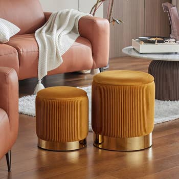 Two round velvet ottomans with gold bases in a living space, showcasing contemporary furniture design