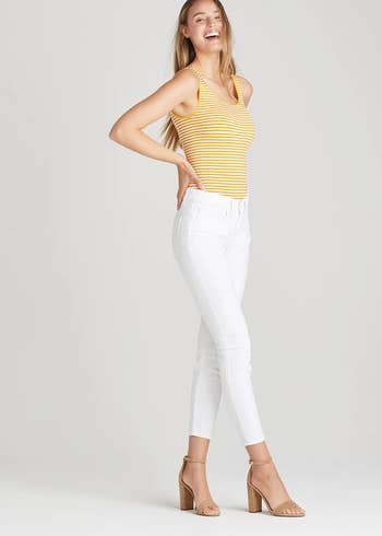 model wearing the yellow striped bodysuit with white jeans and heels