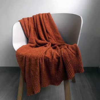 orange soft blanket draped over a white chair