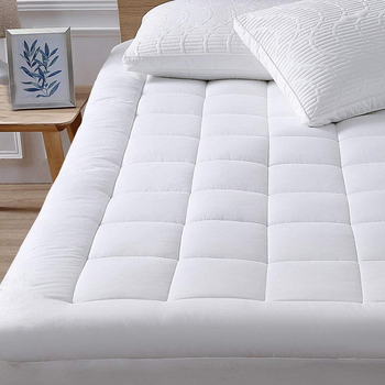 The white mattress pad stretched firm on a mattress 