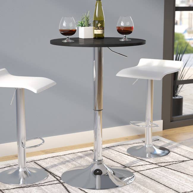 A tall black and silver table with matching chairs and wine