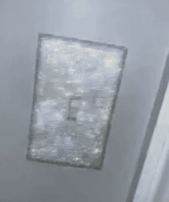 reviewer gif of the silver rhinestone light switch cover showing how shimmery it is
