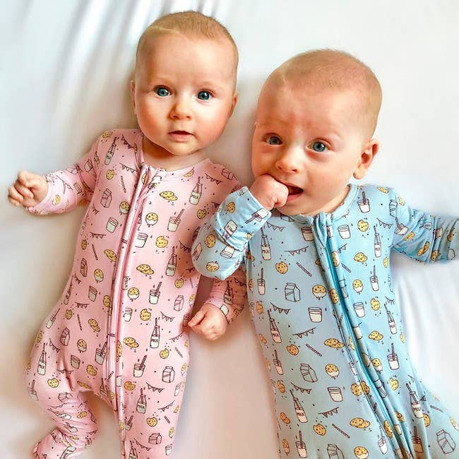 Two infants in patterned onesies with milk and cookies on them