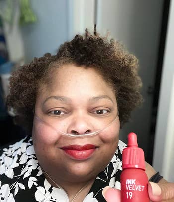 reviewer wearing theared and holding up one of the lip tints