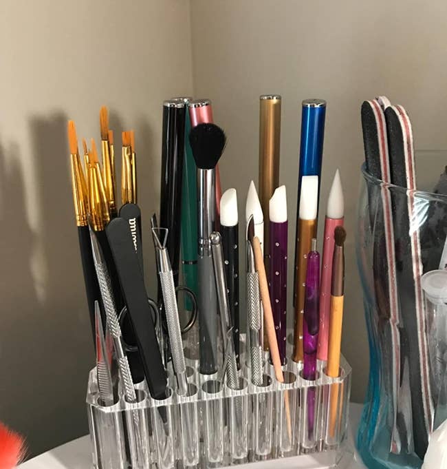 reviewer's transparent holder that stores all their brushes and tools vertically in its three rows of holes