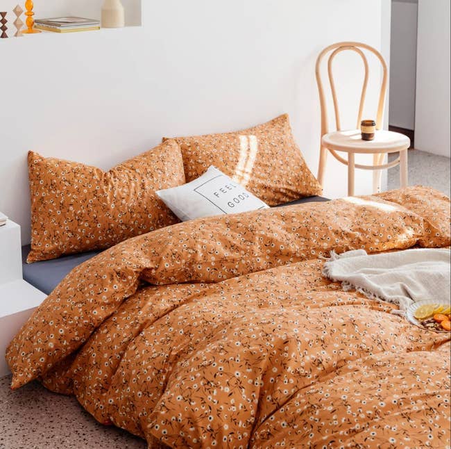 the floral duvet cover on a bed with pillows and a throw blanket