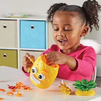 Child model playing with yellow pineapple toy with different faces