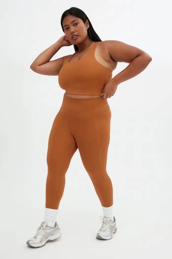 Person wearing a fitted diversion  outfit with leggings and a sports top, paired with sneakers, posing confidently