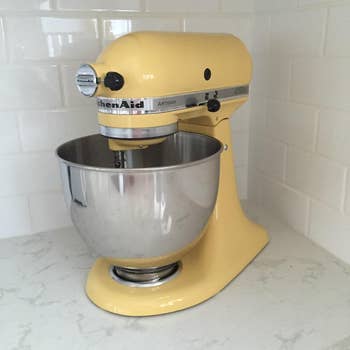 reviewer image of the yellow stand mixer in the corner of a white countertop