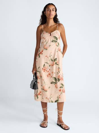 Person successful a floral sundress with spaghetti straps, holding a tiny handbag, wearing strappy sandals