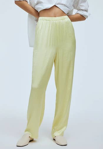 a model wearing the pants in a yellowish green showing off the elastic waistband 