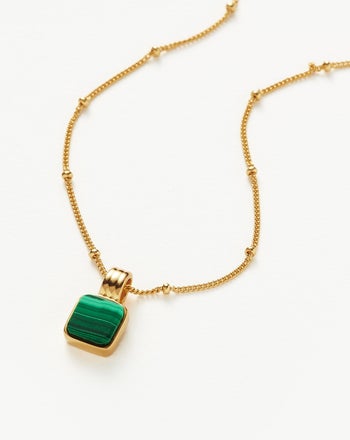 a gold chain necklace with a green square pendant 