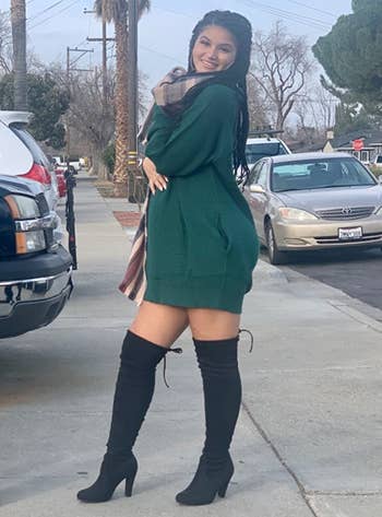 reviewer wearing the green dress with black boots